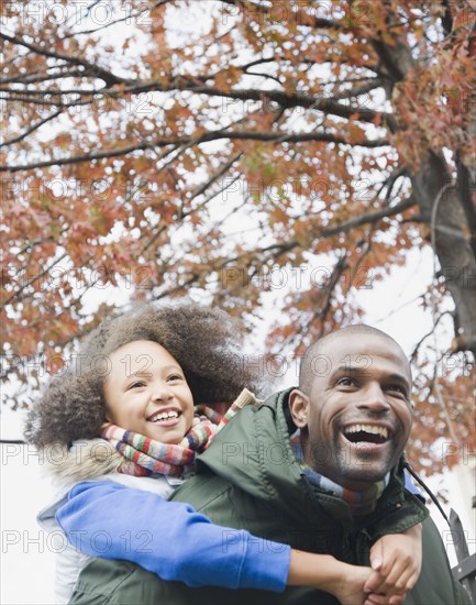 African father carrying daughter piggyback