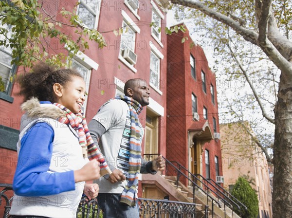 African father and daughter running in city