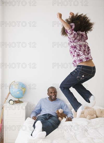 African father and daughter playing on bed