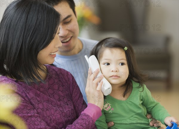 Mother and father holding telephone for daughter