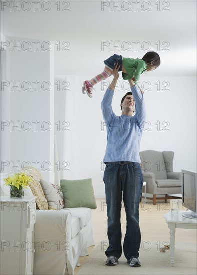 Father holding daughter above head