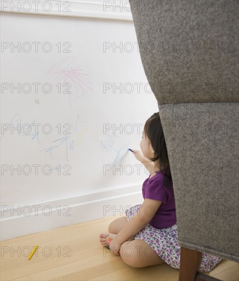 Toddler girl drawing on wall with crayons