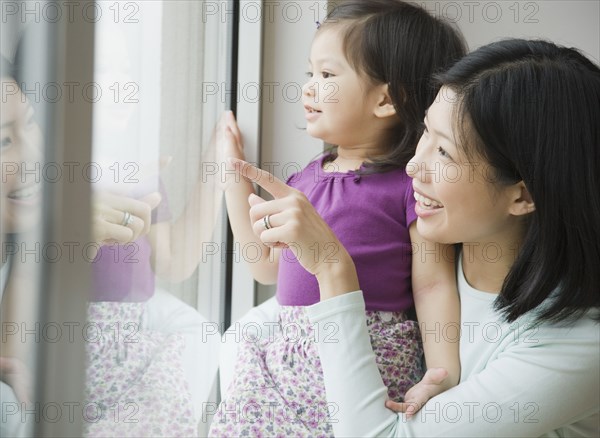 Mother and daughter looking out window