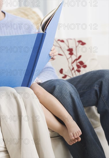 Parents reading to daughter on sofa