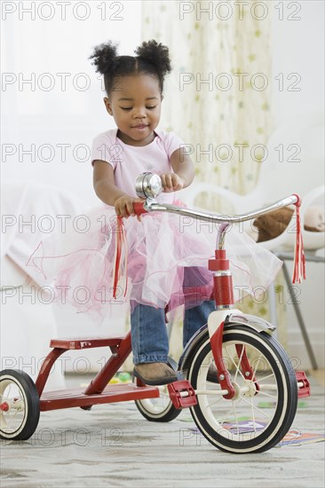 African American girl in costume riding tricycle