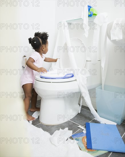 African American girl spreading toilet paper around bathroom