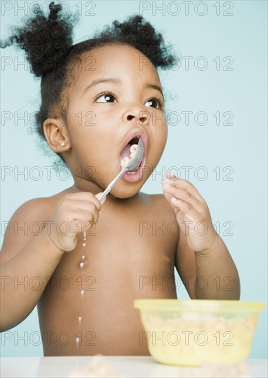 African American girl trying to eat cereal with spoon