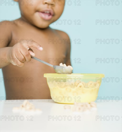 African American girl eating cereal with spoon