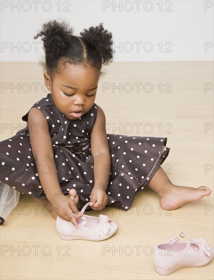 African American girl trying to put shoes on