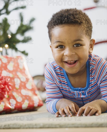 African American boy laying on floor by Christmas tree