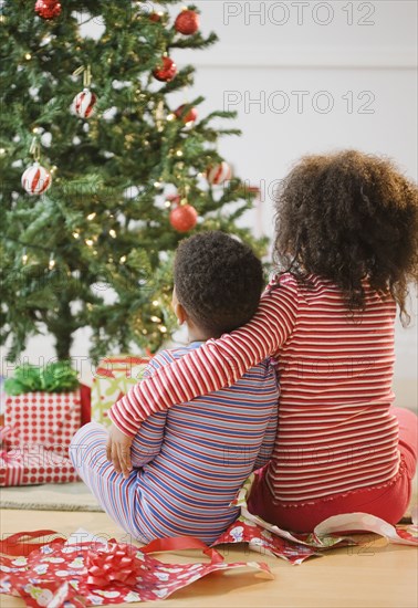 African American brother and sister hugging by Christmas tree