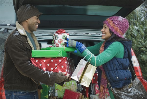 Couple unloading Christmas presents from car trunk