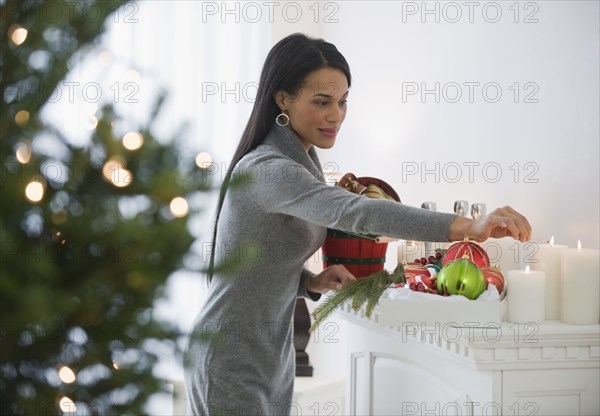 Mixed race woman lighting candles on fireplace mantel