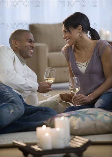 Couple drinking white wine on living room floor