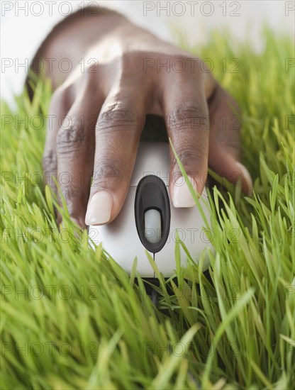 African woman using computer mouse in grass