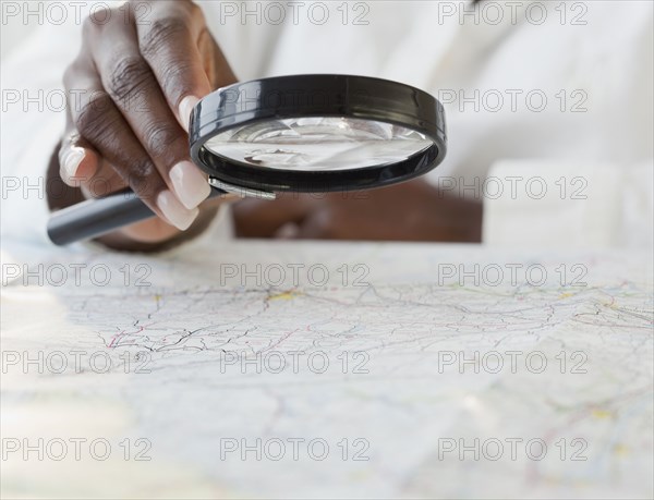 African woman using magnifying glass on map