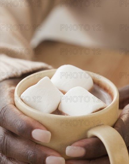 African woman holding cup of hot chocolate and marshmallows