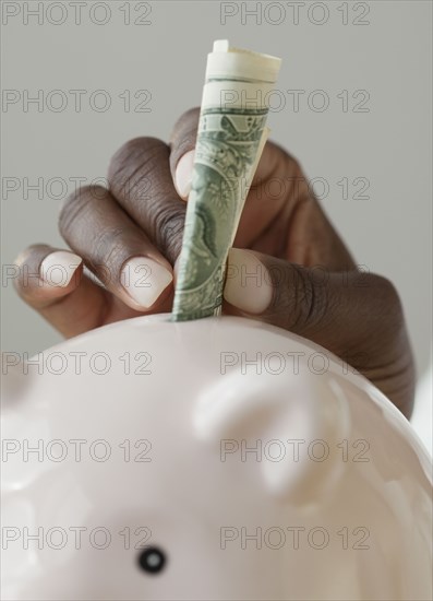 African woman putting money in piggy bank