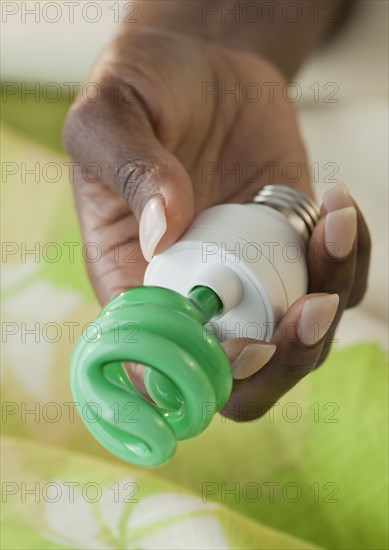 African woman holding CFL light bulb