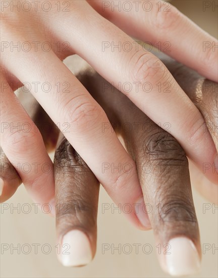 African and Caucasian woman holding hands