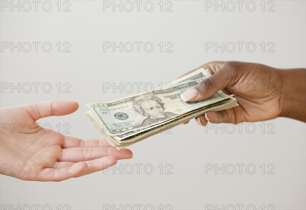 African woman handing over stack of 20 dollar bills