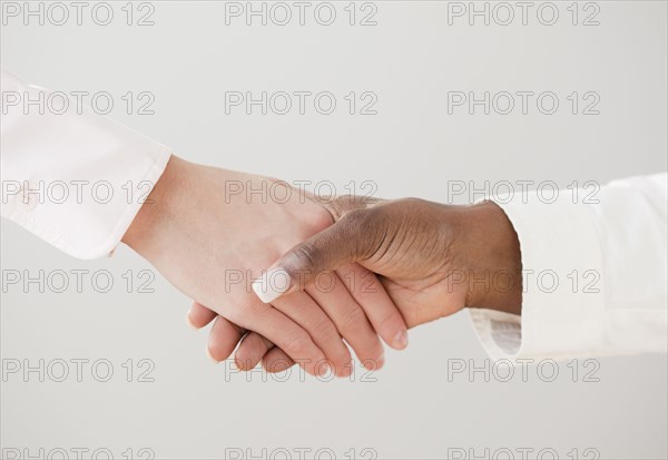 African and Caucasian woman shaking hands