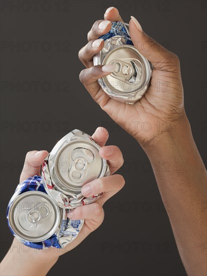 African and Caucasian woman holding crushed cans