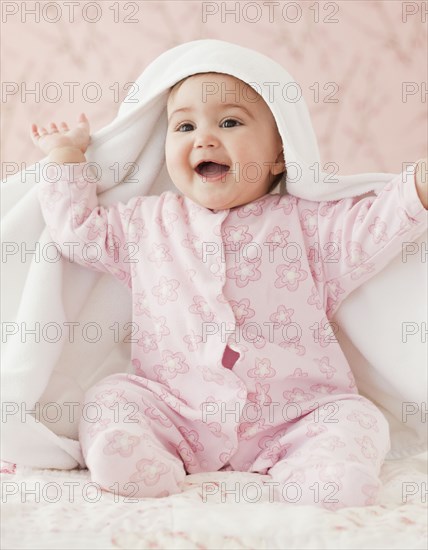 Mixed race baby girl playing peek-a-boo under blanket