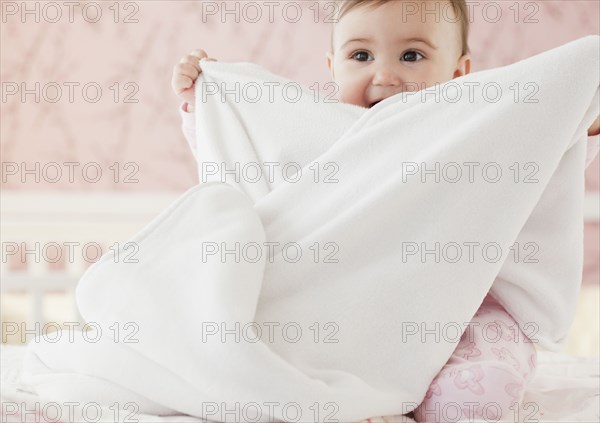 Mixed race baby girl playing with blanket
