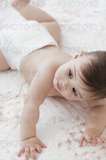 Mixed race baby girl crawling on blanket