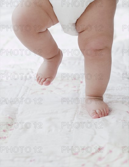 Mixed race baby girl walking on blanket