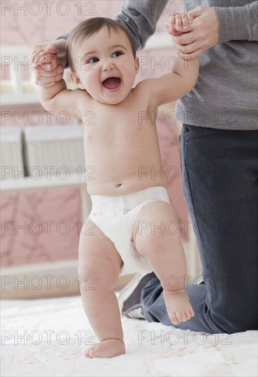 Mixed race mother helping daughter learn to walk