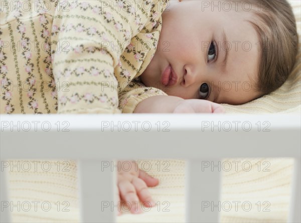 Mixed race baby girl laying in crib