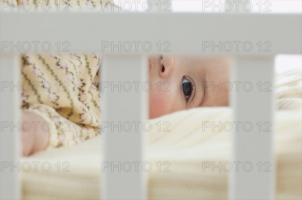 Mixed race baby girl laying in crib