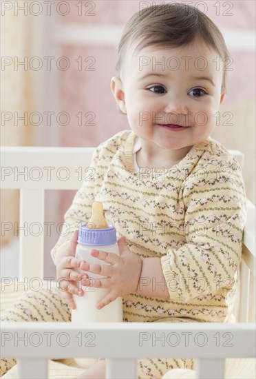 Mixed race baby girl holding bottle