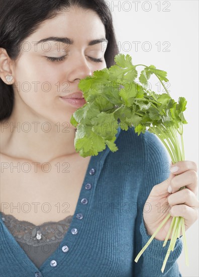 Hispanic woman smelling fresh cilantro