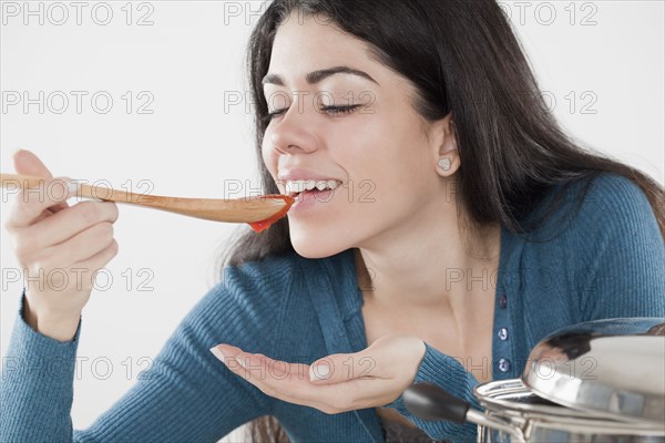 Hispanic woman tasting tomato sauce