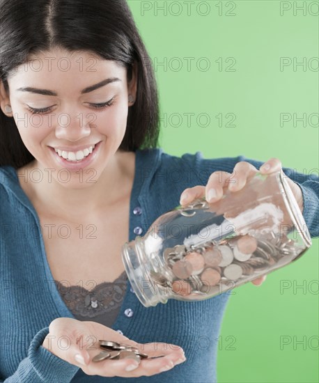 Hispanic woman pouring coins out of jar