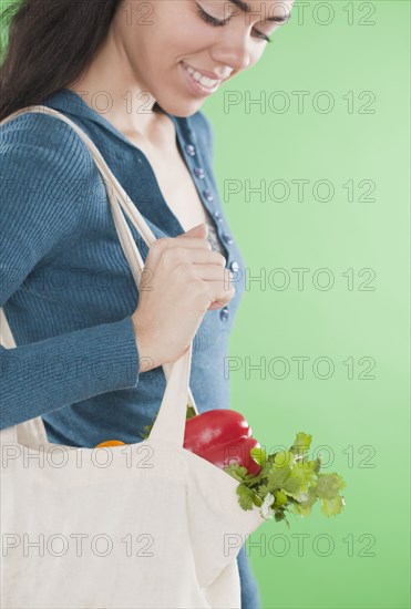 Hispanic woman carrying reusable bag of vegetables