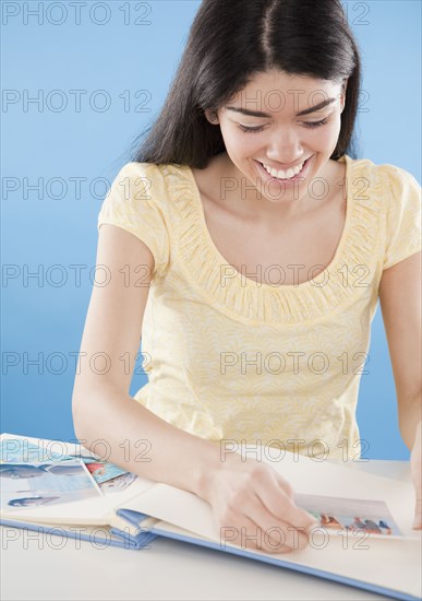 Hispanic woman putting photographs in album