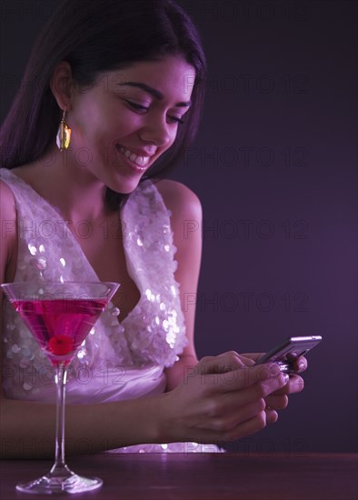 Hispanic woman text messaging in nightclub