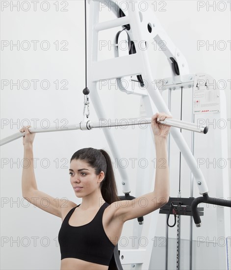 Hispanic woman using weight machine in health club