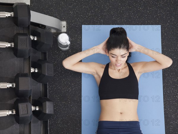 Hispanic woman doing sit-ups in health club