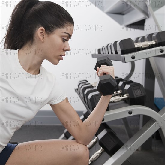 Hispanic woman using hand weights in health club