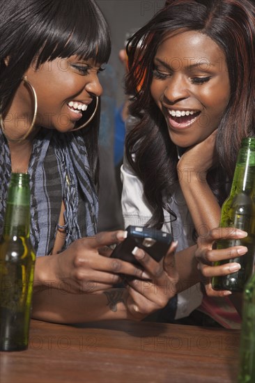 African woman drinking beer and text messaging