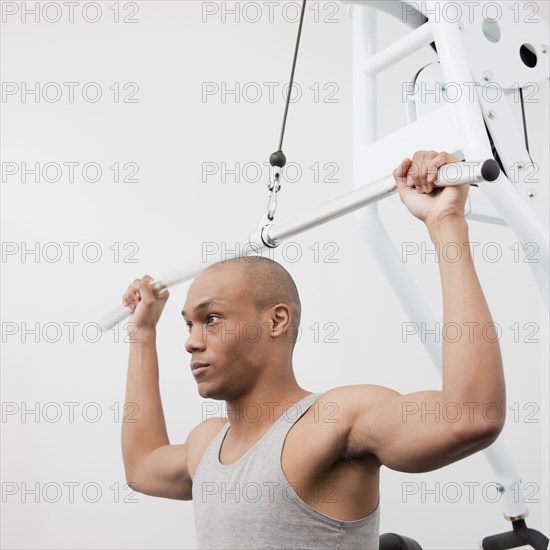 African man using weight machine in health club