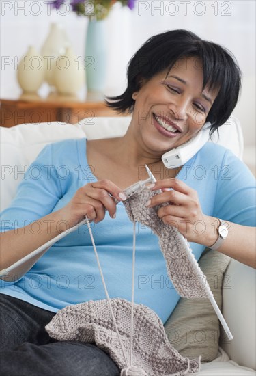 African woman talking on the phone and knitting