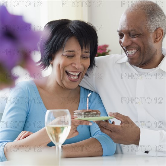 African man giving wife birthday cupcake