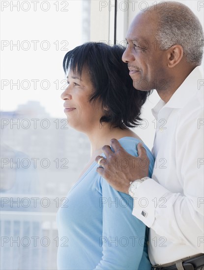 African couple looking out window