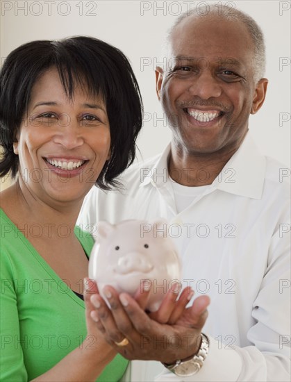 African couple holding piggy bank